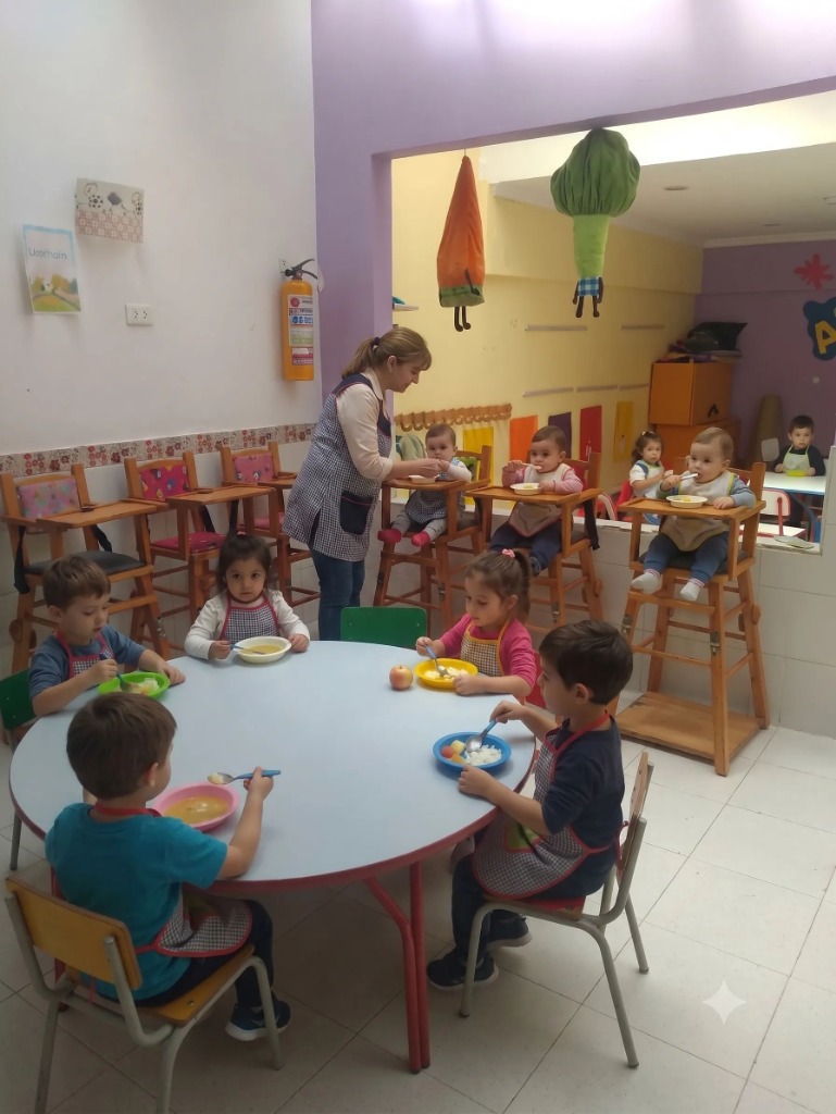 Niños almorzando y compartiendo con su cuidadora en el comedor